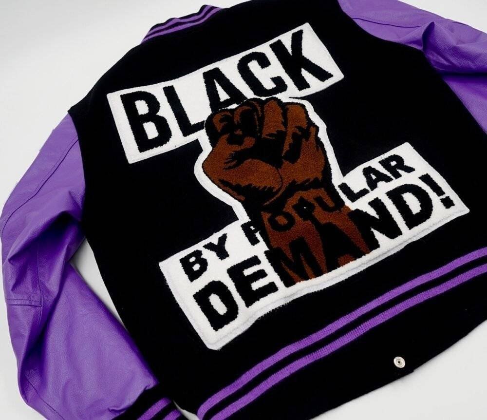 Purple and black varsity jacket with large letter patches on the back.