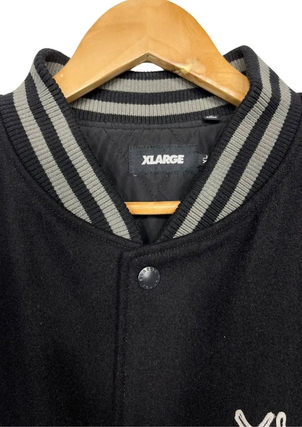 Close-up of the Death Note wool/leather black varsity jacket's front, highlighting the ribbed collar and button closure.