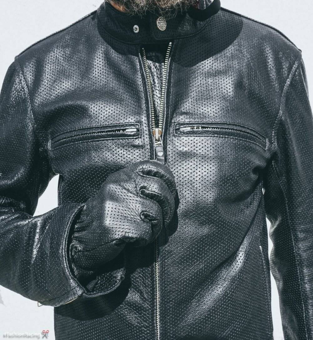 Man wearing a black handcrafted perforated leather jacket with a motorcycle helmet.