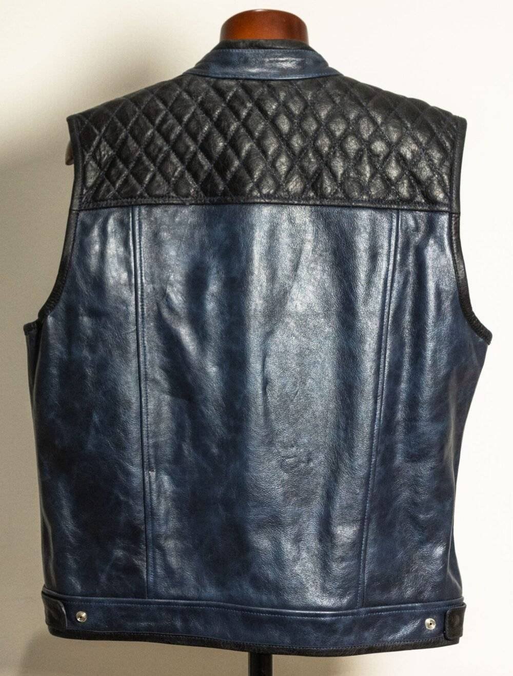 Back view of a handcrafted diamond-stitched blue black leather motorcycle vest with a zipper closure.