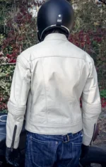 Back view of a model riding a motorcycle wearing a leather cafe racer jacket.