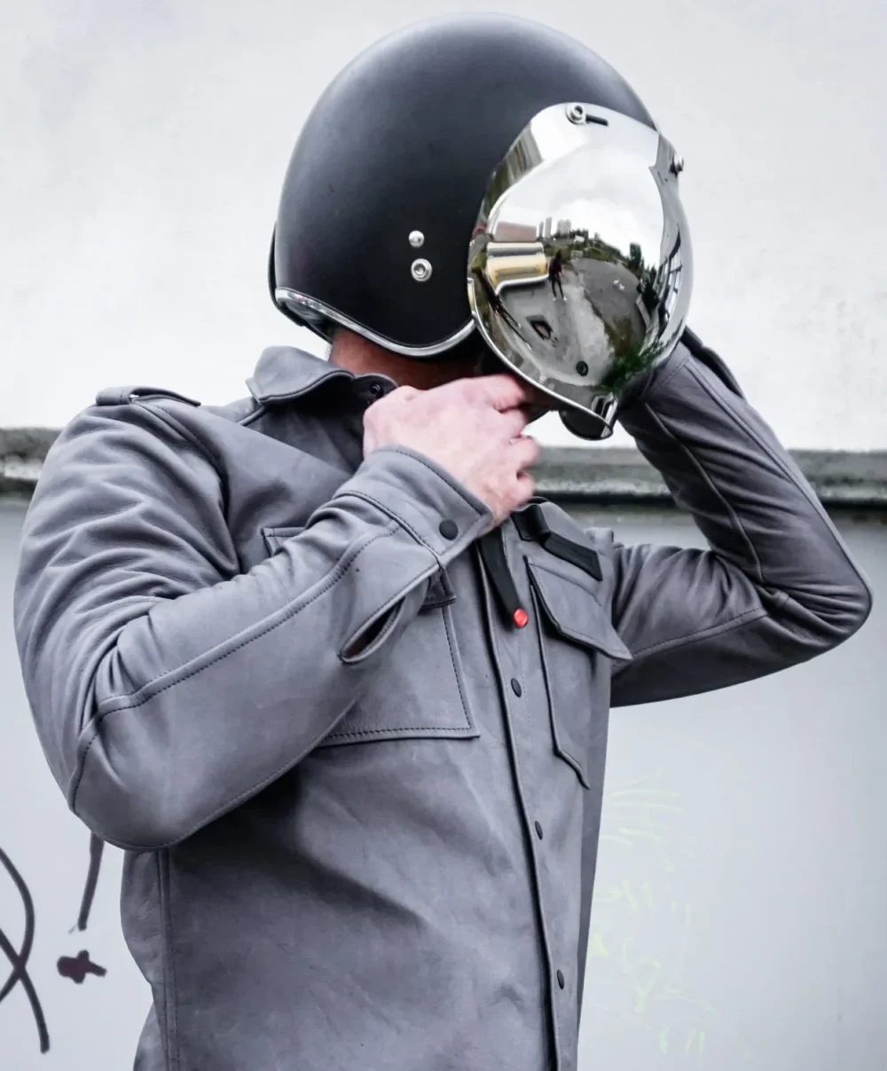 Men's gray leather shirt jacket worn with a helmet, showcasing its versatility and practicality.