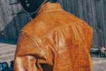 Close-up of the back of an orange brown leather racing jacket, showing the armor protection and stitching details.