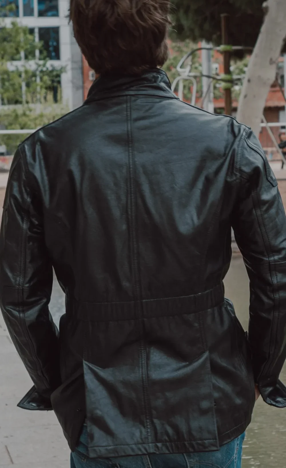 Back view of a black handcrafted leather jacket with a relaxed fit and zippered cuffs.