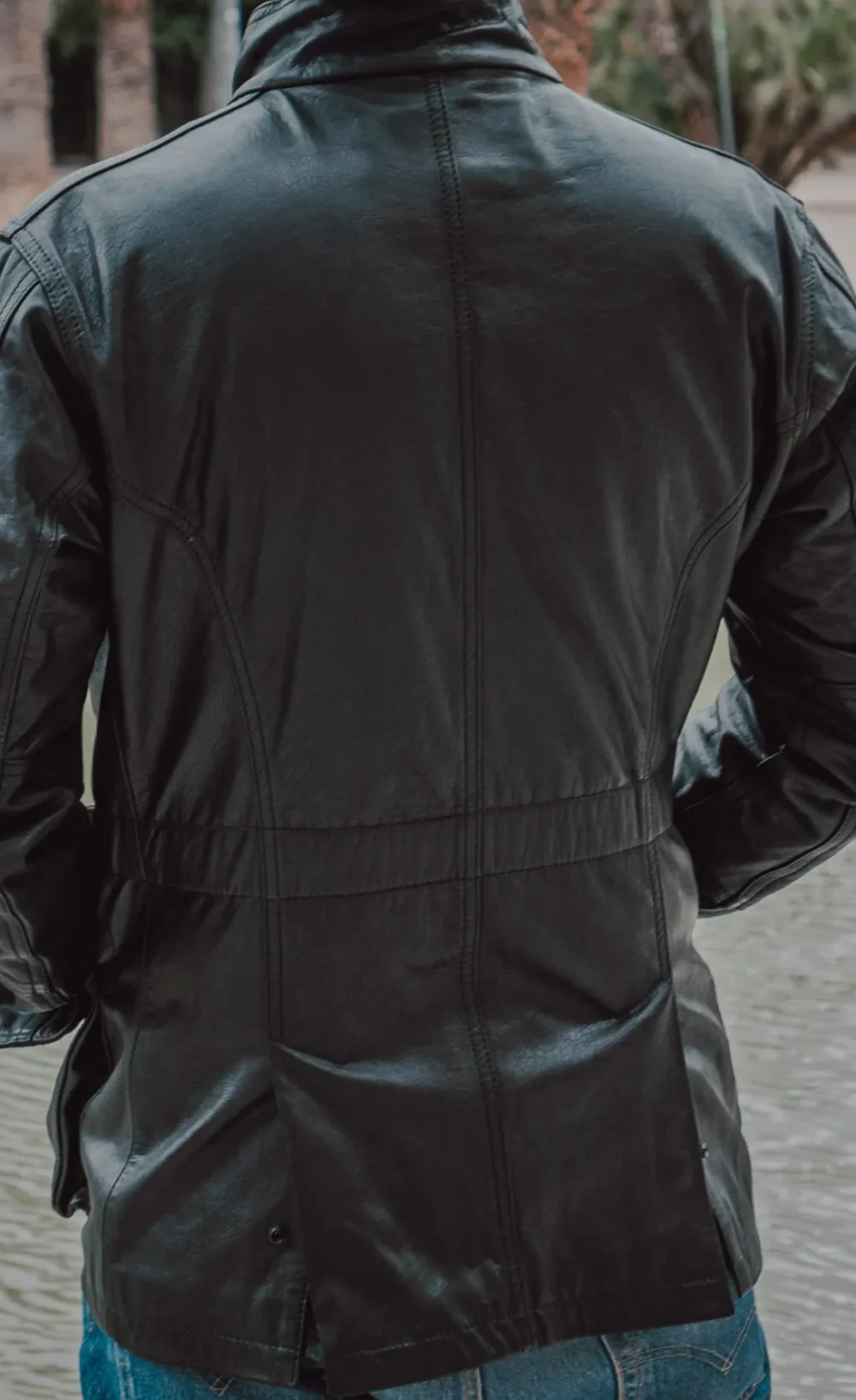 Back view of a black handcrafted leather jacket with a relaxed fit and zippered cuffs.